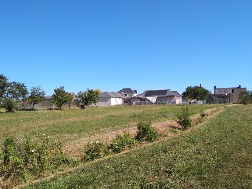 Une partie des bâtiments chauffés par la chaufferie communale - vue depuis de nouvelles haies plantées © ARB-CVL